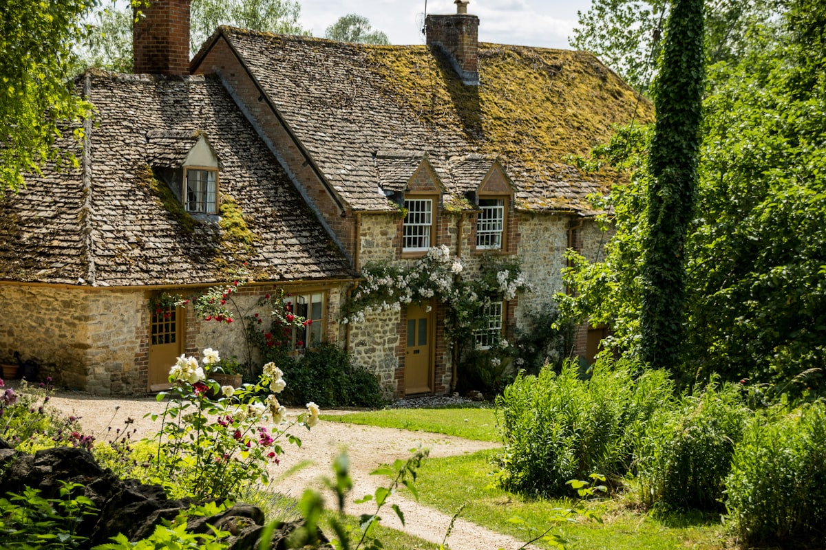Stone cottage in Georgia with moss-covered tile roof, red roses on the walls